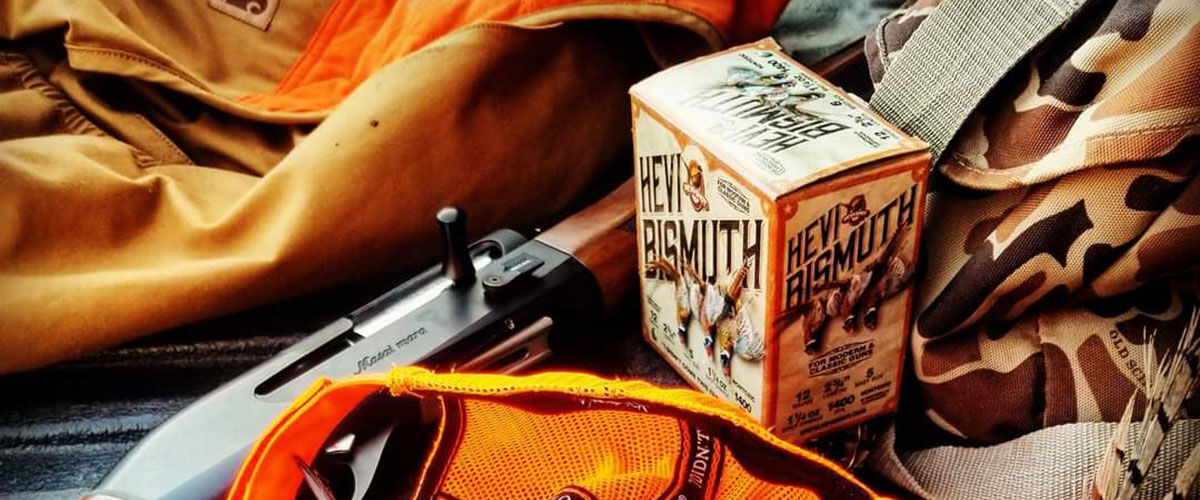 HEVI-Bismuth next to an orange vest and a shotgun