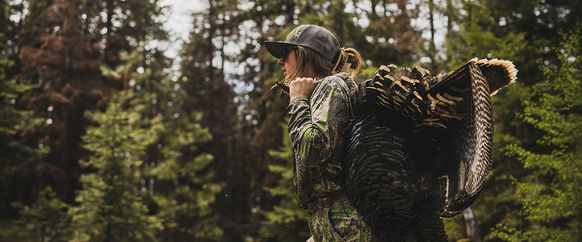 hunter carrying a dead turkey over her shoulder