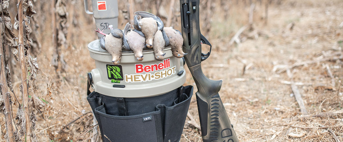 doves sitting on a pail with a shotgun next to it